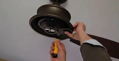 Electrician installing ceiling fan mounting bracket and fixture in Overland Park, KS