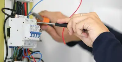 Electrician installing and adjusting circuit breakers in an electrical panel in Overland Park, KS