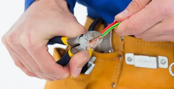 licensed electrician securing electrical wiring with professional tools during service work in Overland Park, KS