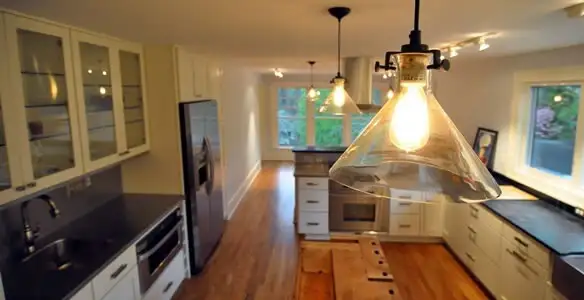 Residential electrician installing modern indoor light fixture in a home in Overland Park, KS