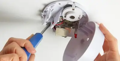 Certified technician wiring smoke detector during installation in Overland Park, KS